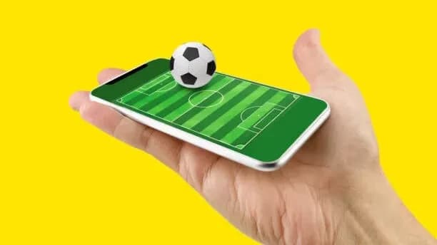 celular com imagem de campo de futebol e bola em cima para representar apostas em futebol