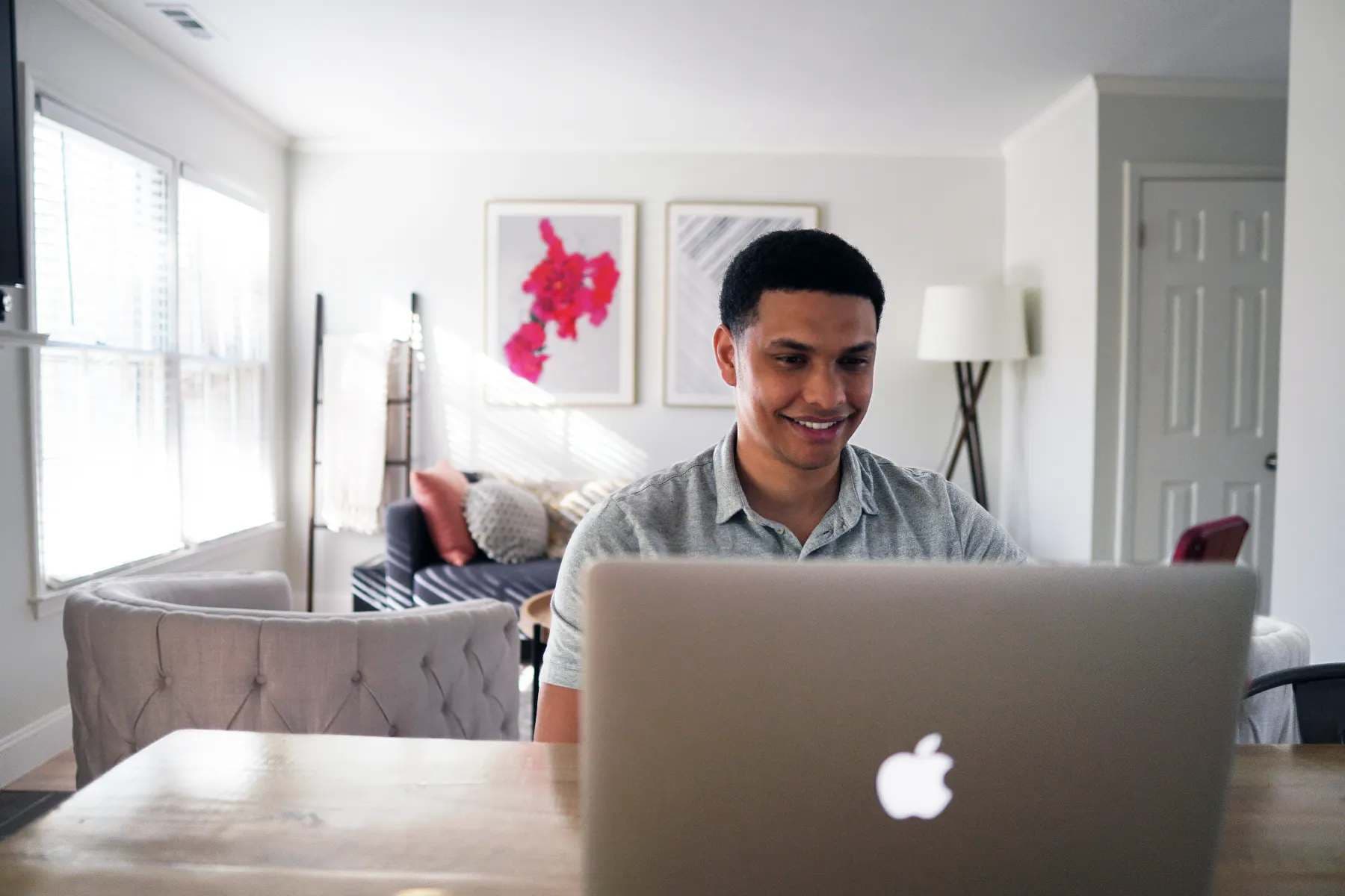 Imagem de um homem usando um macbook, sentado na sala