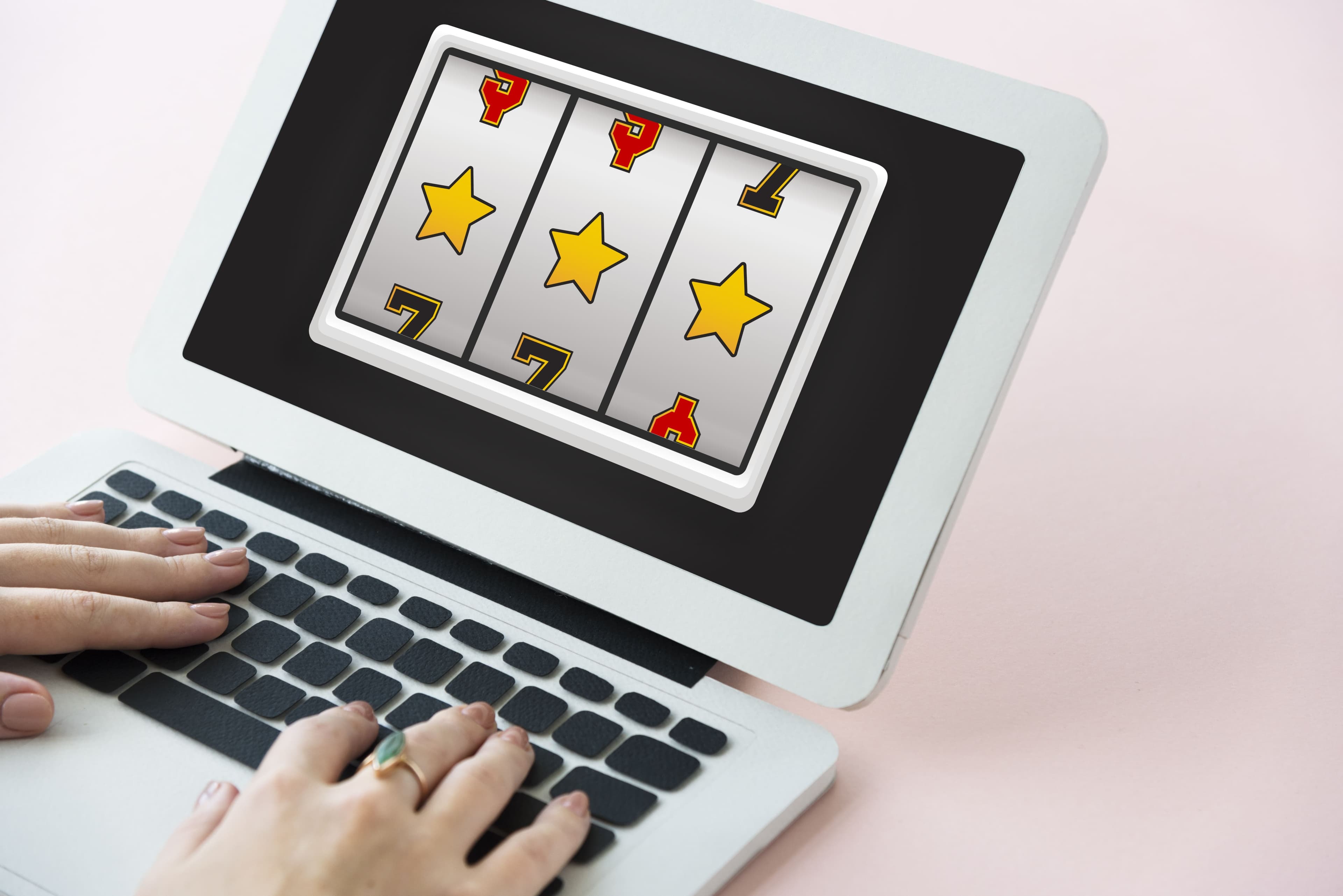 A imagem mostra um notebook branco, com um jogo de cassino acontecendo em uma plataforma de 1 real