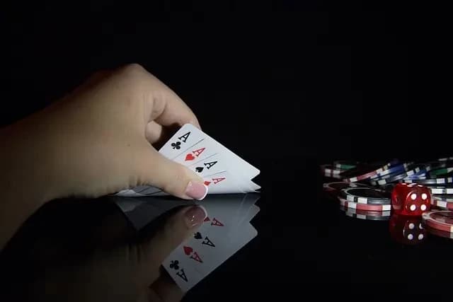 mão colocando cartas de baralho na mesa ao lado de dados e moedas de poker