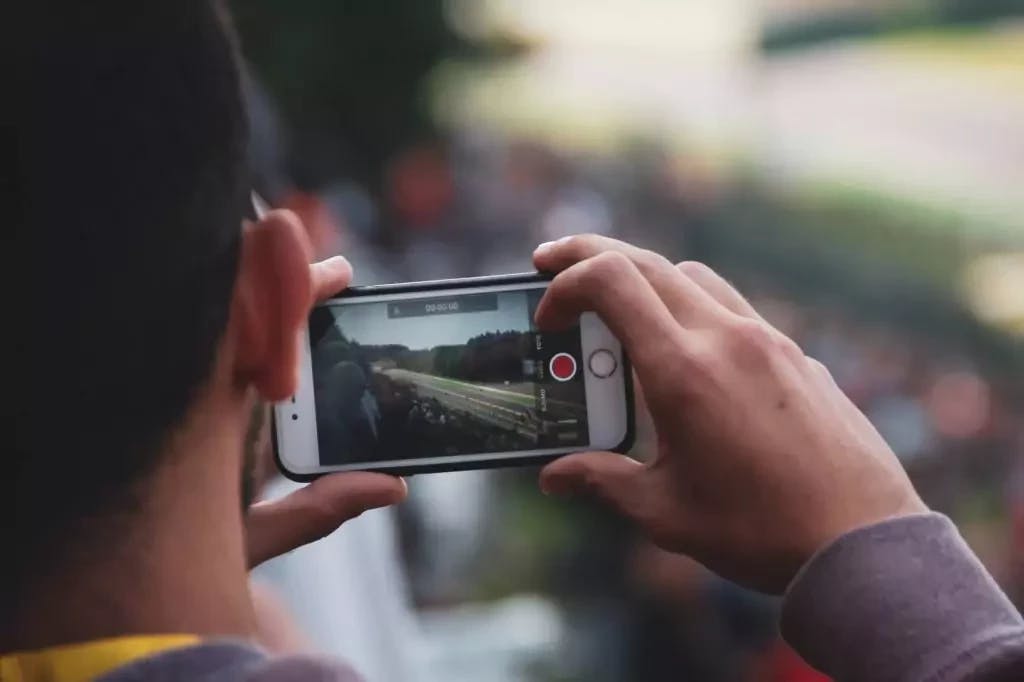 Imagem de um homem filmando uma corrida de Fórmula 1