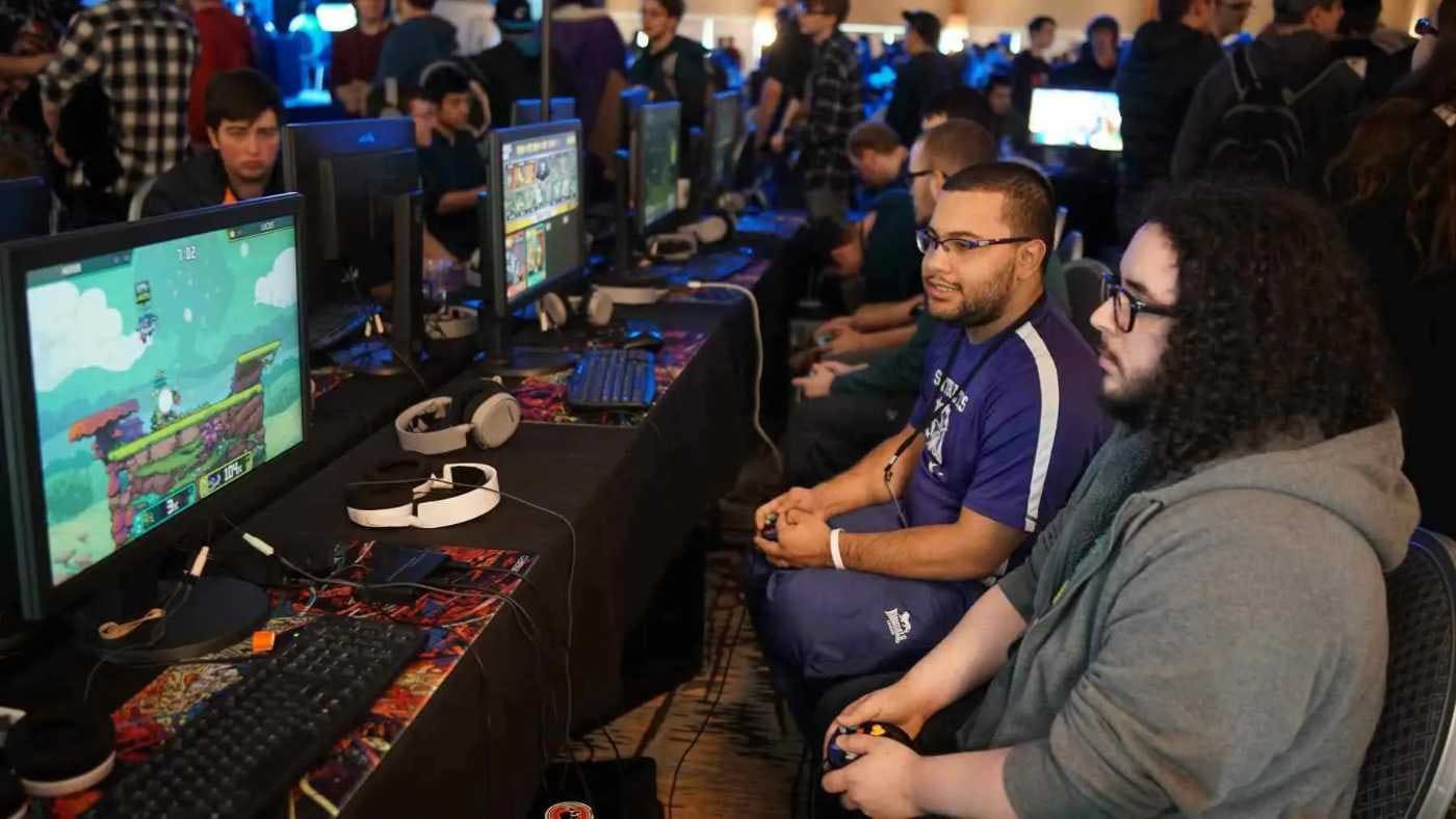 Imagem de vários homens jogando um jogo de computador em algo que parece ser uma competição de eSports