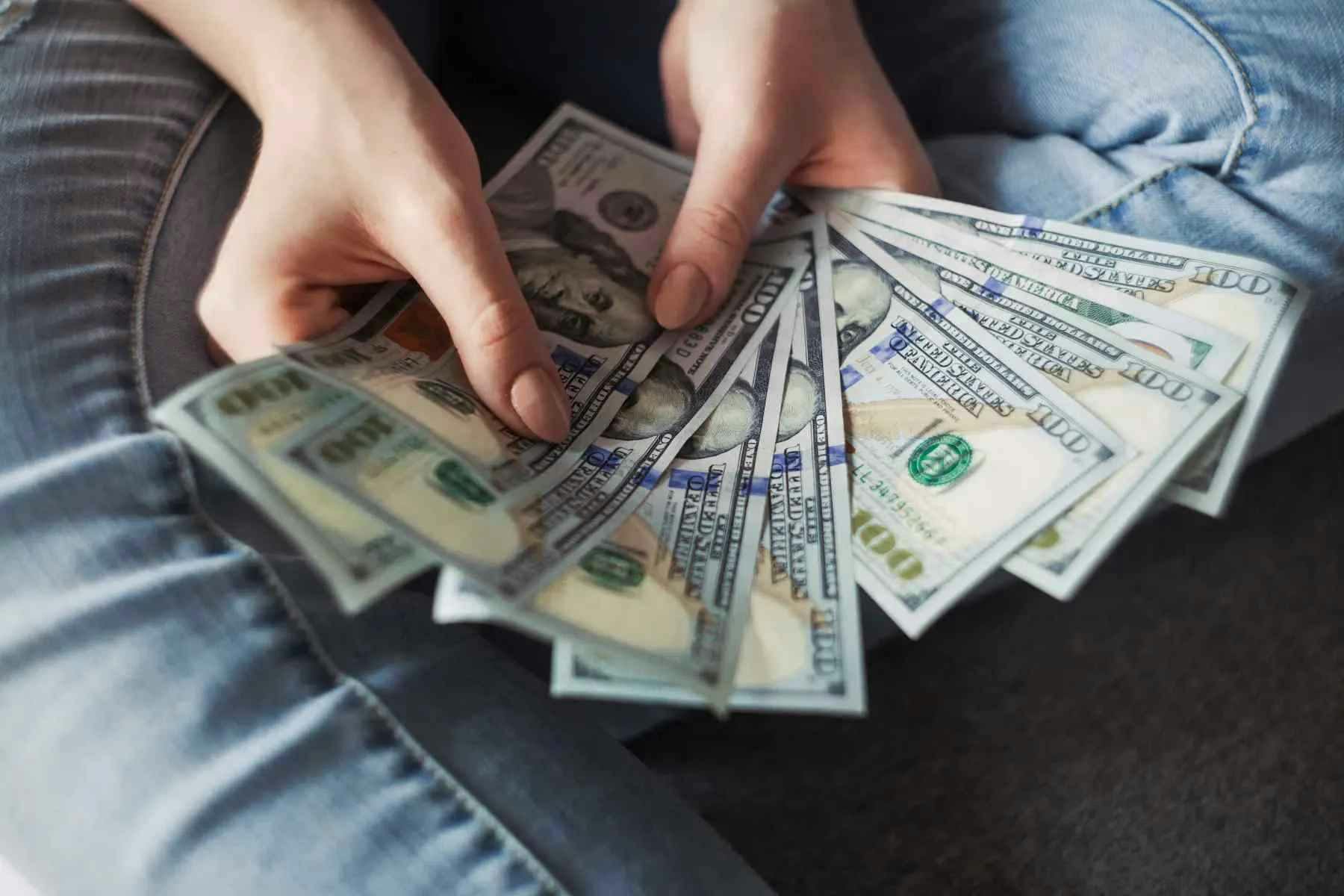 Imagem de uma pessoa segurando várias notas de dólar na mão